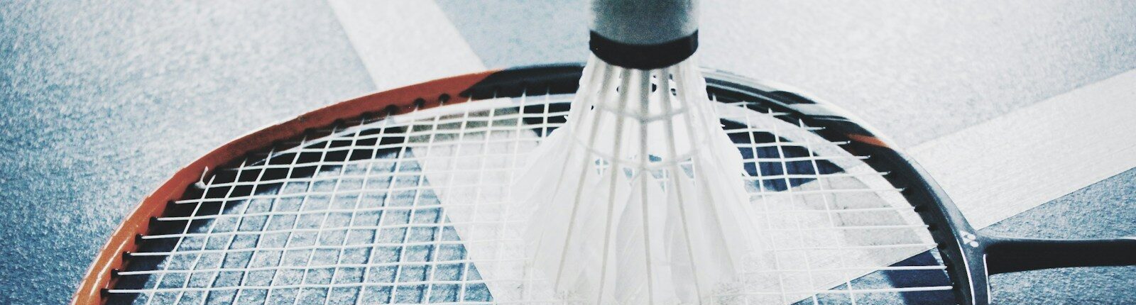 white shuttlecock on brown and black badminton racket placed on floor